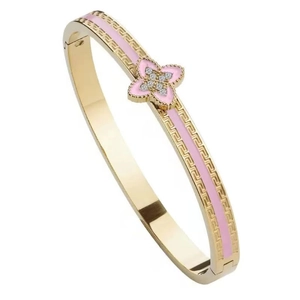Detail view of gold clover bangle with pink enamel, crystals, and Greek meander engraving