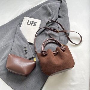 Brown vintage matte suede bucket bag set with ring handle on grey blazer background