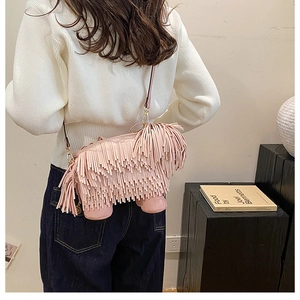 Close-up of pink fringe crossbody bag with metallic adjustment buckle on shoulder strap