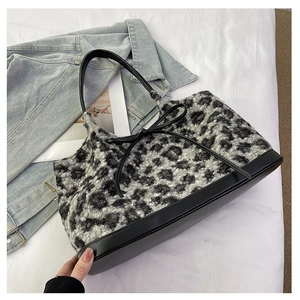 Detail of plush leopard print tote bag with black leather handles and bow accent