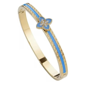 Detailed view of gold clover bangle with blue enamel, zircon petals and Greek key pattern