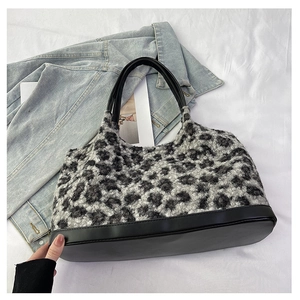 Detail of grey leopard faux fur tote bag with black leather straps on denim background