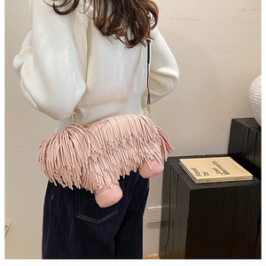 Rear view of a pink fringe dog-shaped crossbody bag worn by a model in a minimalist room