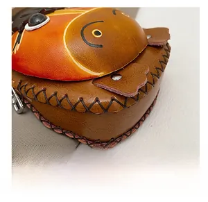 Detail shot of vintage brown leather bag featuring orange animal face and cross-stitch seams
