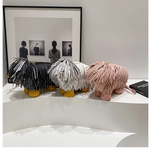Detailed close-up of quirky dog-shaped fringe handbags in black, white, and pink leather