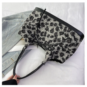 Detail view of leopard print plush bag with black leather straps and decorative bow tie
