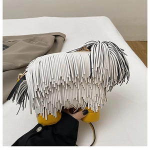Detail of unique white tassel dog crossbody bag with yellow feet and gold chain strap