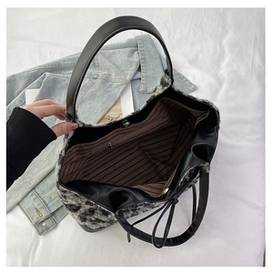 Detailed interior of leopard plush handbag showing striped lining and zipper pocket
