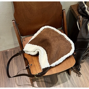 Détail du sac sous l'aisselle en daim café avec bordure en fourrure blanche et boucle dorée