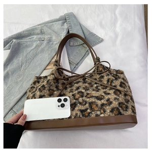Detail of plush leopard print tote bag featuring brown leather straps and bow accent