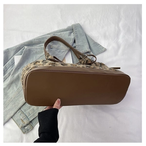 Detail of wide flat base on leopard print plush tote bag with brown faux leather bottom