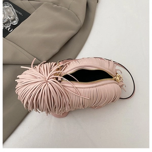 Detailed shot of pink fringe dog-shaped crossbody bag with gold zipper and thin black strap