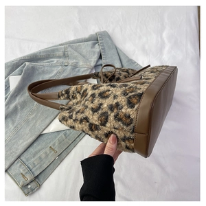 Detail of plush leopard print tote bag with brown faux leather base and drawstring closure