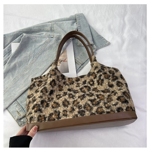 Detail of plush leopard print tote bag with brown faux leather handles and bottom base