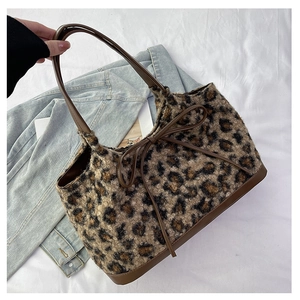 Detailed shot of leopard print plush tote bag with brown leather bow and handles