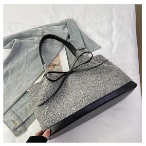 Close-up of grey woven tote bag with black leather straps and decorative bow detail