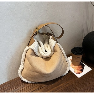 Détail du sac hobo en daim kaki et fausse fourrure blanche sur une table en bois
