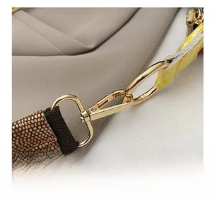 Detail showing golden metal lobster clasp and brown lizard texture strap on shoulder bag