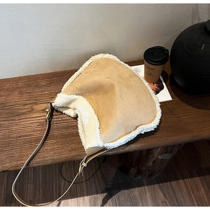 Détail du sac à bandoulière en peluche camel sur un banc en bois avec accessoires