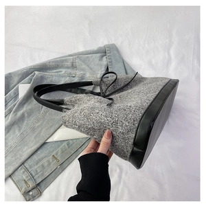 Detail of grey knitted tote bag with black faux leather base and bow knot detail