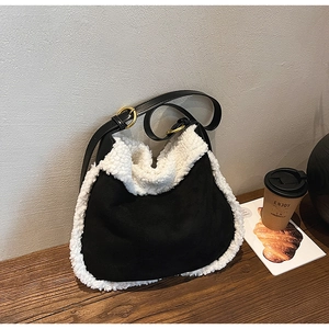 Detail of contrast fuzzy tote bag with black suede body and white fleece trim on wood table