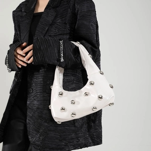 White leather dumpling bag with silver studs and metal balls in modern shoulder bag style
