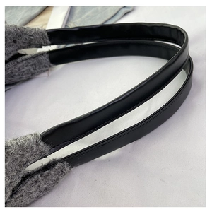 Detail of black leather handles and grey faux shearling texture on women's tote bag