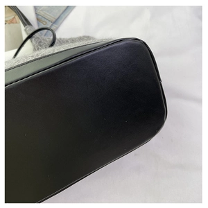 Close-up of the durable black leather base and soft grey plush fabric of the tote bag