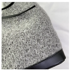 Macro shot of grey wave-texture plush fabric and black leather trim on a tote bag