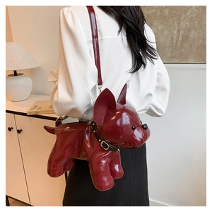 Detail of dark red puppy crossbody bag in glossy faux leather worn by a model
