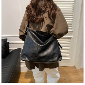 Detail showing the large capacity black tote bag with adjustable wide strap on model