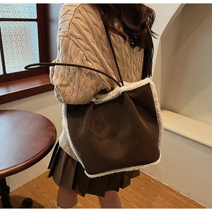 Brown suede shoulder bag with cream faux shearling trim worn by a model in a cafe