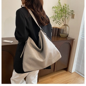 Large light grey tote bag in soft leather texture shown as a stylish crossbody for travel