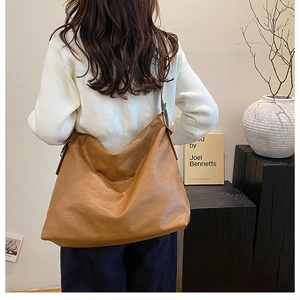 Brown large capacity tote bag shown on shoulder in a minimalist aesthetic setting