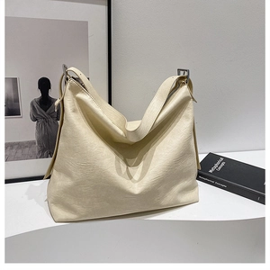 Detailed macro view of cream faux leather tote with soft texture and silver buckle