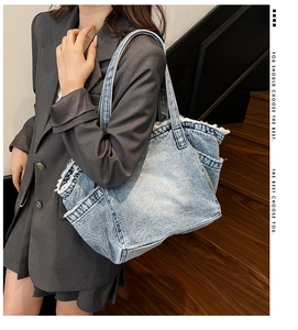 Detail of light blue washed denim tote bag with frayed edges and double straps