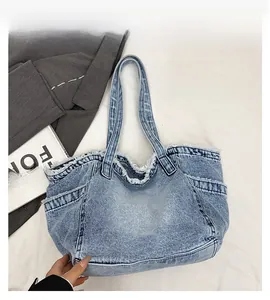 Close-up of a large blue denim tote bag featuring distressed edges and a side pocket detail