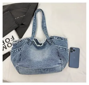 Detail of washed denim tote bag with frayed edges and external pocket with phone scale