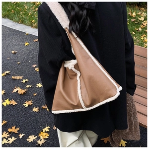 Detail of dark brown pebbled faux leather bag with white shearling trim and wide strap