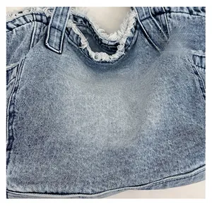 Close-up of washed blue denim fabric texture and raw frayed edge detail on tote bag