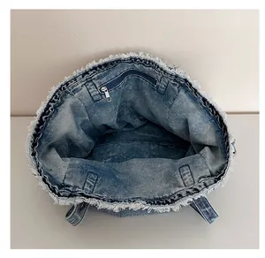 Detail view of denim tote bag showing interior zipper pocket and frayed edges