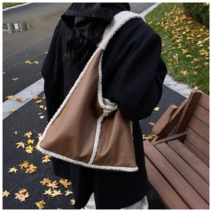 Detailed back view of a large brown leather tote bag with white shearling trim on a shoulder