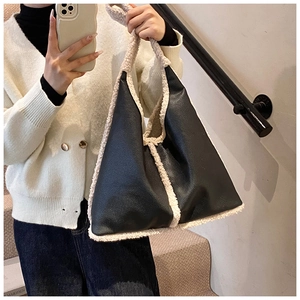 Detail of black faux leather tote bag featuring cream white faux shearling trim accents