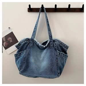 Macro shot of retro blue denim tote bag featuring distressed frayed edges and side pockets