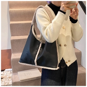 Detail view of large tote bag with black leather and cream faux shearling trim on stairs