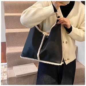 Detail of a large black leather shoulder bag with plush beige faux fur trim worn by a model