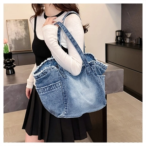 Close-up of washed blue denim tote bag featuring stylish frayed edges and side pocket detail