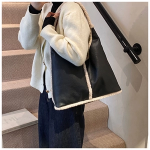 Detail of black pebbled leather tote with off-white faux shearling trim on model