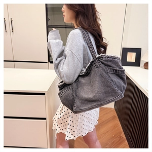 Detail of grey washed denim tote bag showing wide side pockets and frayed edge texture