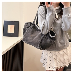 Detail of dark gray washed denim tote bag featuring fringe edges and a spacious design